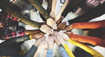 Diverse group of hands coming together in a circle, colorful