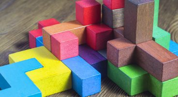 Multi-size and shaped colored wood blocks stacked randomly on wood surface