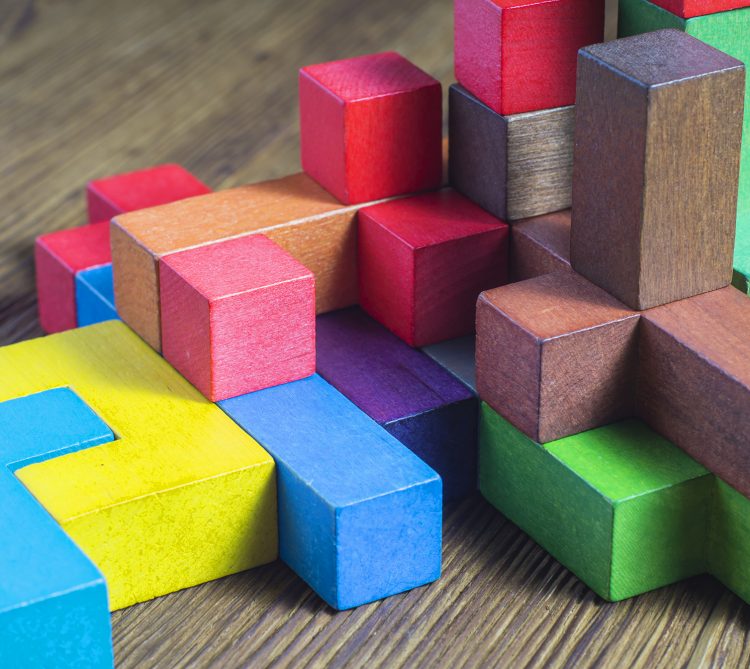 Multi-size and shaped colored wood blocks stacked randomly on wood surface